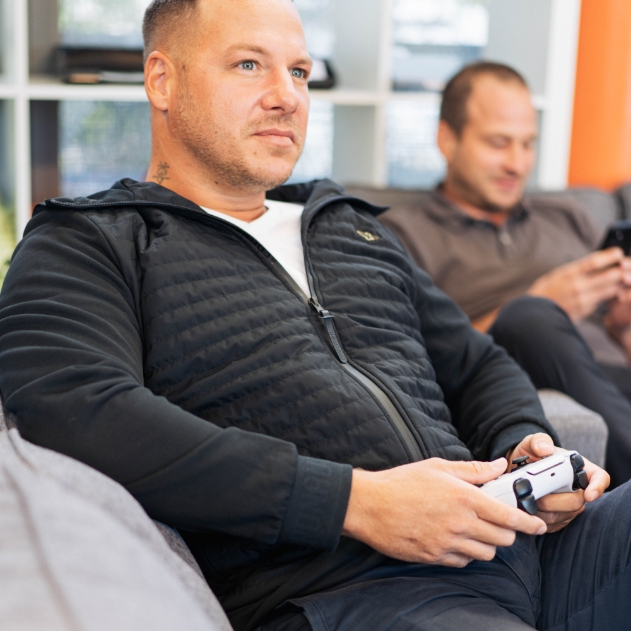 Rene Haslauer auf der Couch mit Playstation 5 Controller